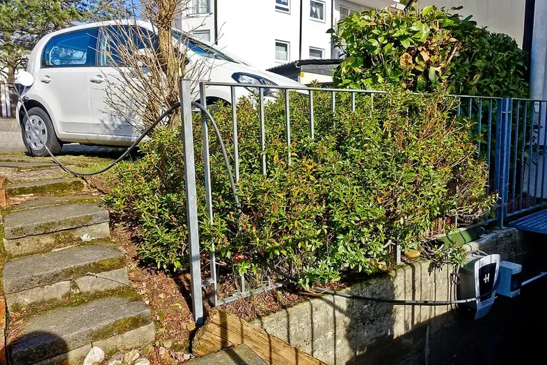 Elektrische auto aan een laadkabel van een wallbox aan de gevel van een woonhuis