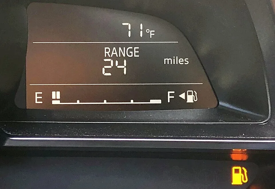 Dashboard met een bijna lege brandstofmeter en het oranje reservelampje aan