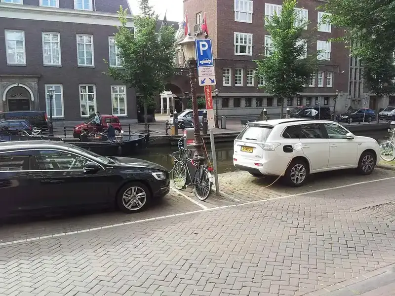 Geparkeerde auto's langs een gracht bij een laadpunt in Amsterdam