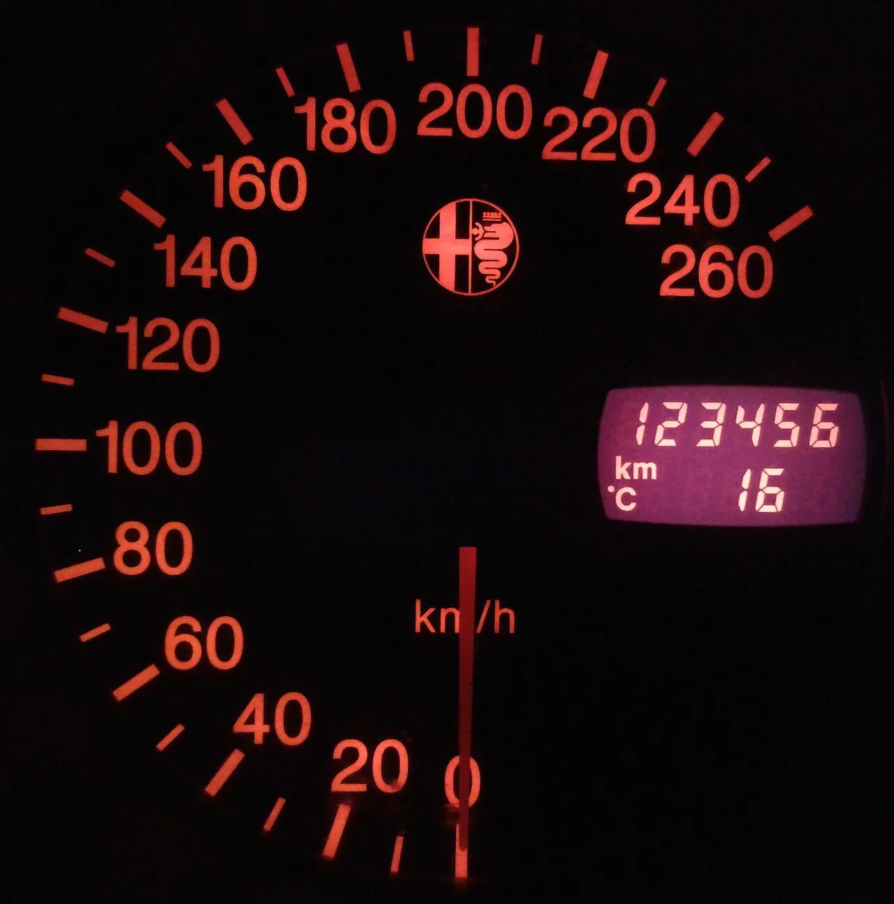 Verlichte snelheidsmeter van een auto in het donker met op de kilometerteller precies 123456 km