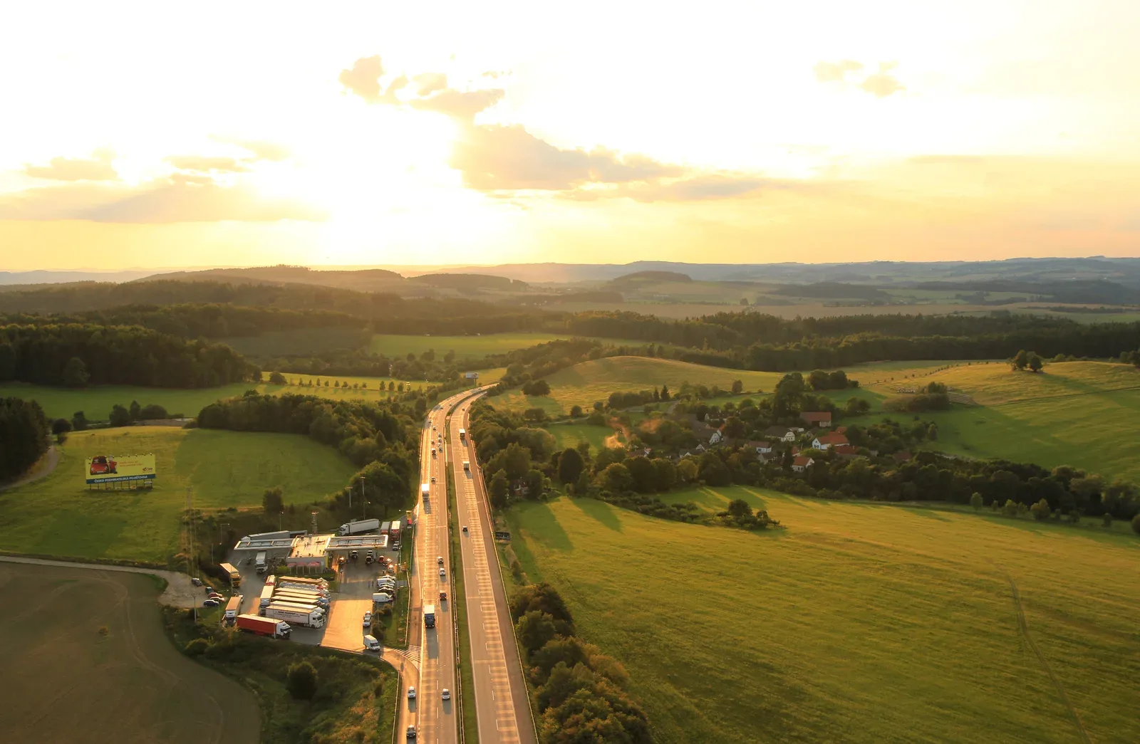 Luchtfoto van snelweg D1 bij Ostředek in Tsjechië met een wegrestaurant en tankstation tussen groene heuvels