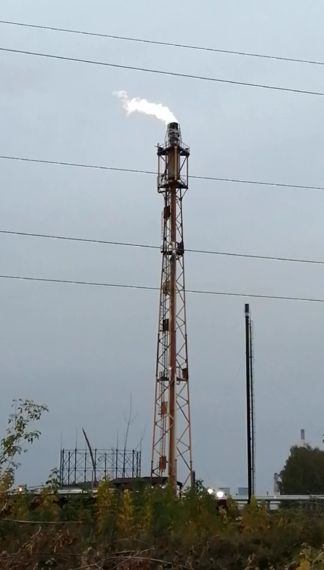 Fakkelmast met witte rookpluim bij de olieraffinaderij in Rjazan, Rusland, onder een grijze lucht