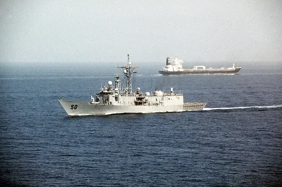 Een Amerikaans marineschip vaart langs een olietanker vlak na de Straat van Hormuz