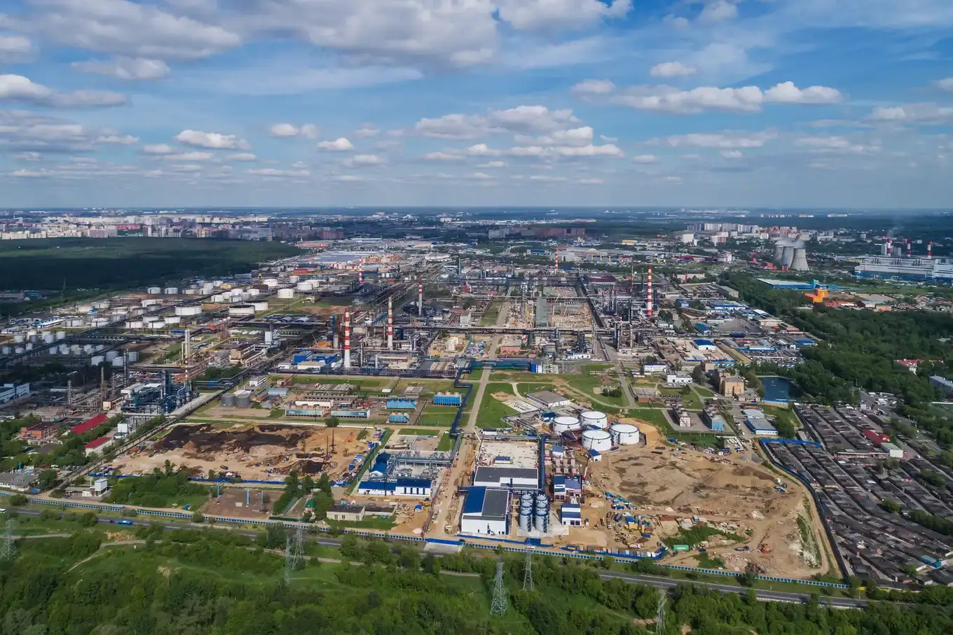 Luchtfoto van de olieraffinaderij in Moskou met opslagtanks, schoorstenen en installaties onder een blauwe lucht