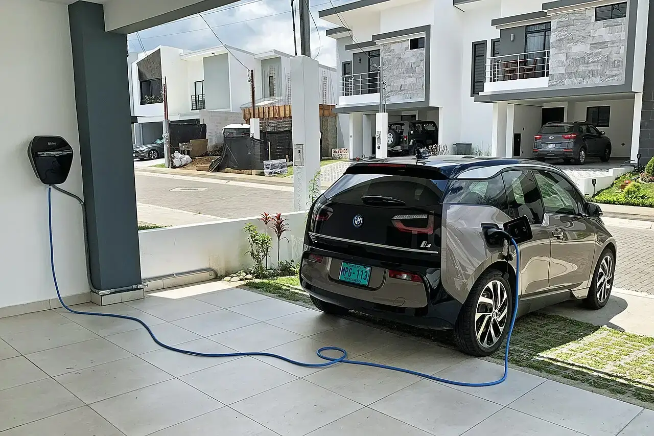 Elektrische auto aan de laadkabel van een thuislader bij een woonhuis