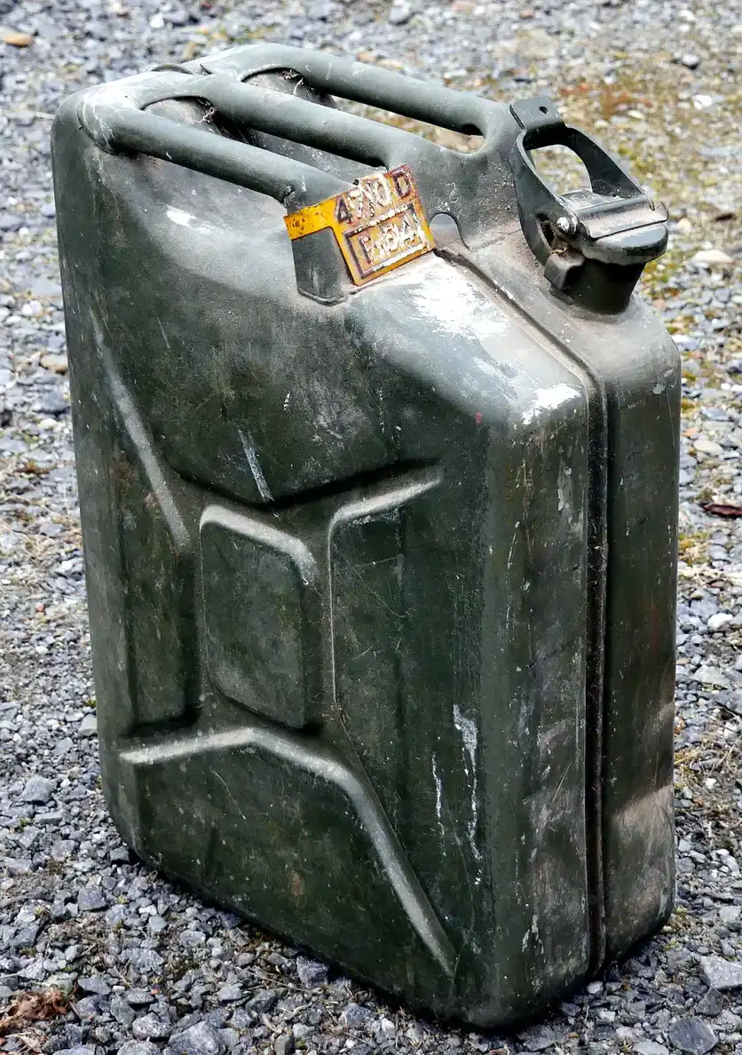 Een oude, groene metalen jerrycan op grind