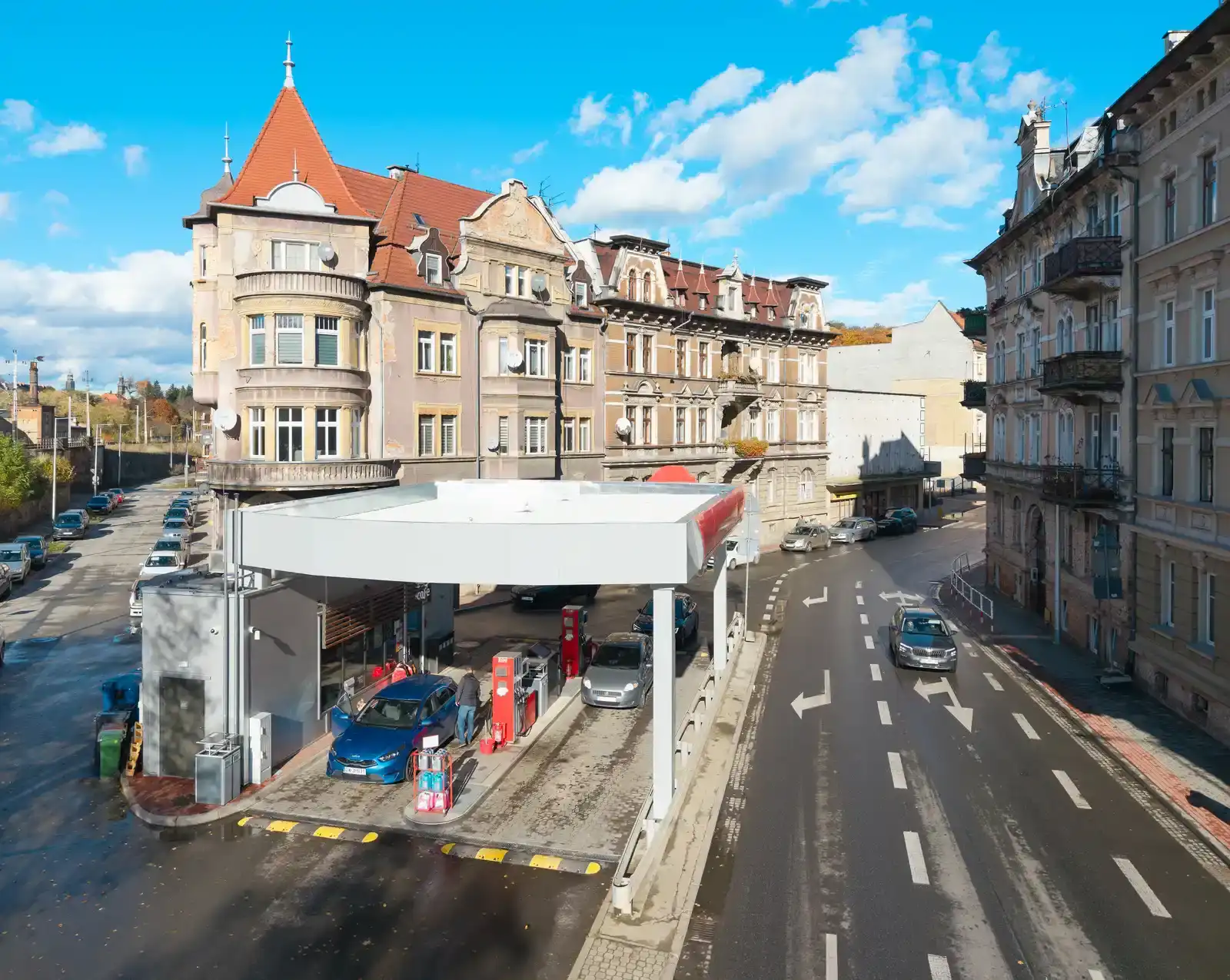Tankstation in het Poolse Kłodzko, waar een automobilist tankt, met oude gevels op de achtergrond