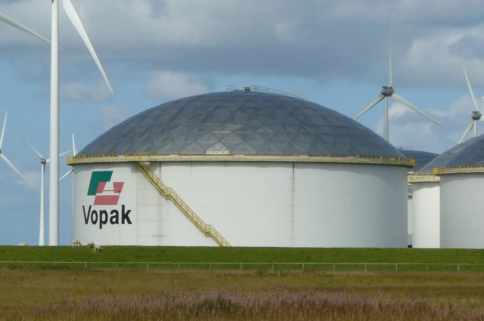 Witte olieopslagtanks in de Eemshaven met windmolens op de achtergrond