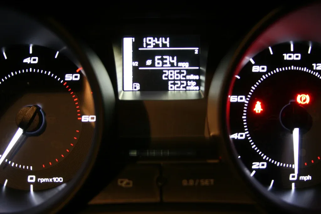 Dashboard van een auto in het donker met in het middendisplay het gemiddelde verbruik en de gereden afstand