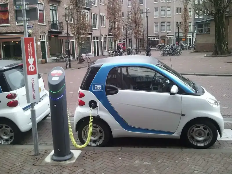 Een kleine elektrische auto wordt opgeladen aan een laadpaal in Amsterdam