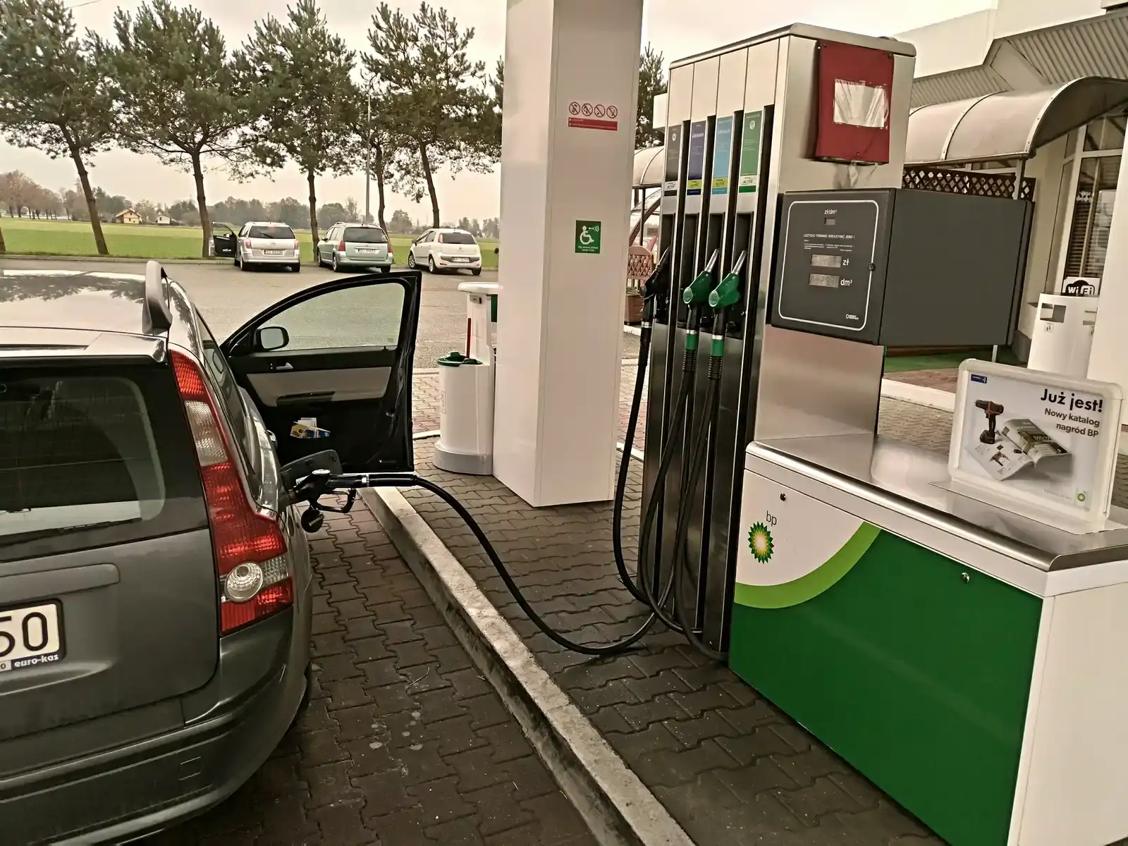 Auto staat aan de pomp en wordt volgetankt bij een tankstation