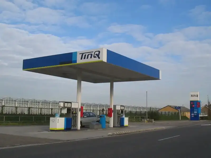 Tankstation met pompen en een prijzenpaal langs een Nederlandse weg