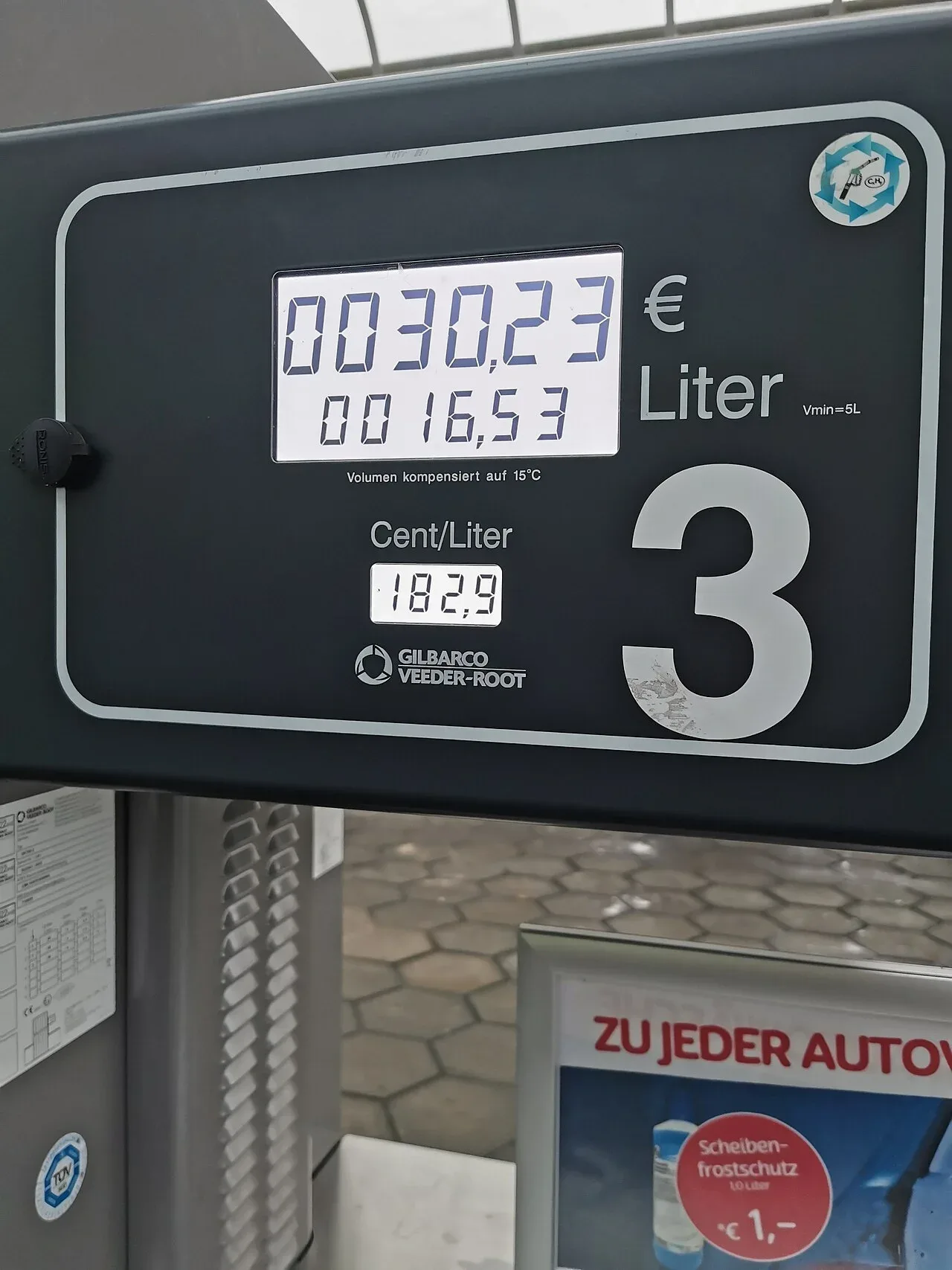 Display van een Duitse benzinepomp met 30,23 euro en 16,53 liter, met daaronder de tekst Volumen kompensiert auf 15 °C